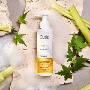Cutis D Shampoo bottle with hemp seed oil and CBD on a textured stone background with green leaves nearby